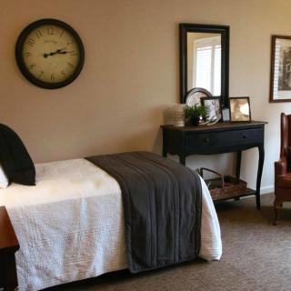 A cozy bedroom with a single bed, decorative clock, and mirror.