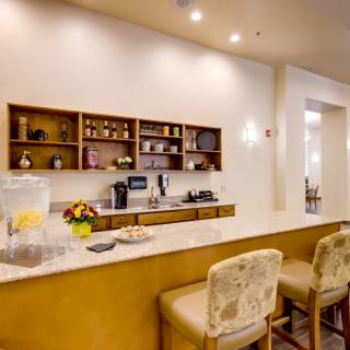 A modern kitchen interior with a counter, bar stools, and a coffee station.