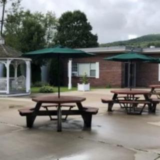 An outdoor patio area with picnic tables and umbrellas on a cloudy day.