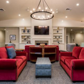 A modern living room featuring red sofas, a central chandelier, and a fireplace with a mounted TV.