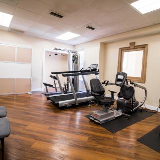 A small home gym with exercise equipment, including a treadmill and recumbent bike.