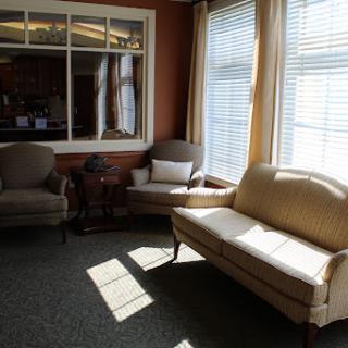 A cozy living room bathed in natural light, featuring a classic sofa and armchairs.