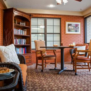 A cozy living room with a bookshelf, comfortable chairs, and a table by the window.