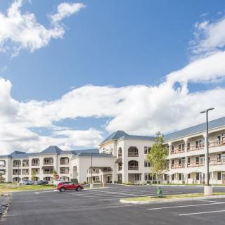 A large hotel building with a spacious parking lot and cloudy sky.