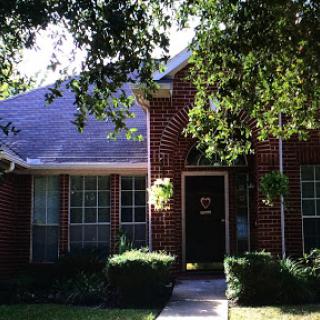 A charming brick house surrounded by greenery.