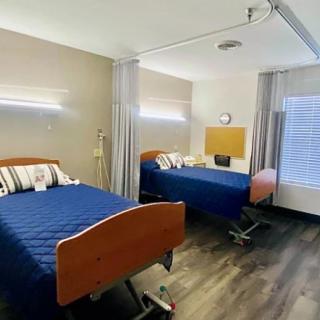A well-lit hospital room with two adjustable beds and privacy curtains.