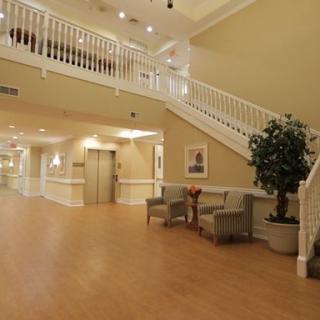 A spacious lobby area with a staircase, elevator, seating, and decorative plants.