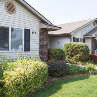 A well-maintained residential house with lush landscaping and a manicured front yard.