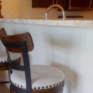 A kitchen area featuring a wooden bar stool with a cushioned seat and a marble countertop.