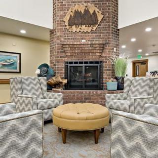 A cozy lounge area featuring a brick fireplace, patterned armchairs, and a round ottoman.