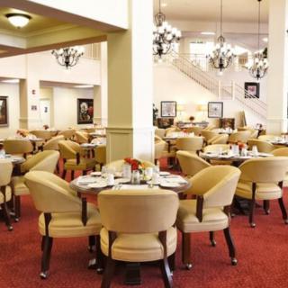 An elegant restaurant dining area with neatly arranged tables and chairs, complemented by chandeliers.