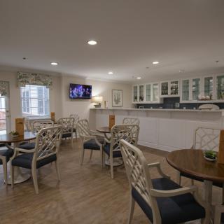 A cozy dining area with tables, chairs, and a kitchenette.