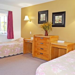 A cozy bedroom with twin beds, wooden furniture, and decorative wall art.