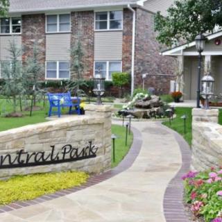 A well-maintained apartment complex entrance with a landscaped outdoor area and pathway.