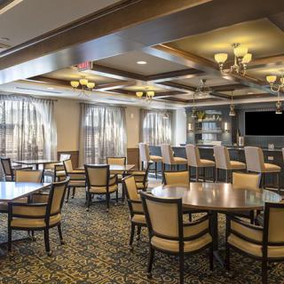 A cozy restaurant interior featuring multiple tables and chairs, with a bar area in the background.