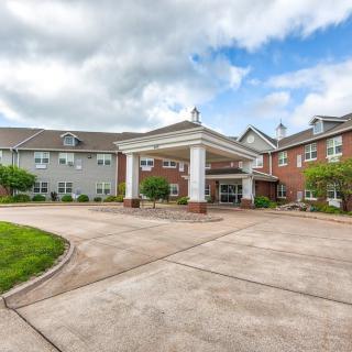 A residential building with a grand entrance featuring columns and a spacious driveway.