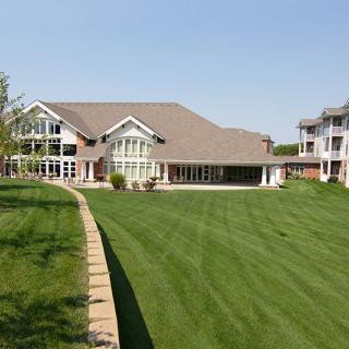 A large luxury home with a spacious green lawn and modern architectural design.