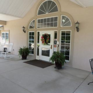A welcoming building entrance with a decorated door and potted plants.