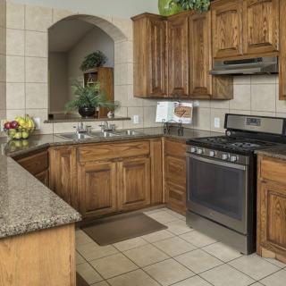 A traditional kitchen featuring wood cabinets, granite countertops, and a modern stove.