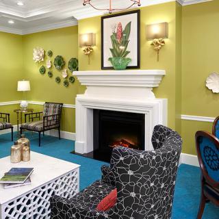 A stylish living room with a fireplace, decorated with green walls and a blue carpet.