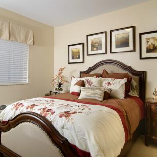 A cozy and elegantly decorated bedroom with a wooden bed frame, floral bedding, and framed artwork on the wall.