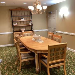 A cozy dining room with a wooden table and chairs, illuminated by a chandelier.