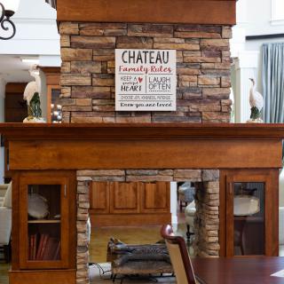 A rustic stone and wood fireplace with decorative elements and a sign on top.