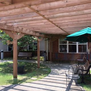 A peaceful garden patio with a wooden pergola and outdoor seating area.