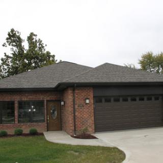 A modern brick house featuring a spacious garage and manicured landscaping.