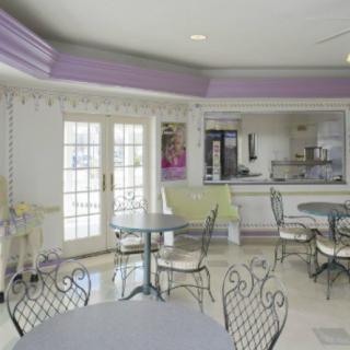 A cozy cafe interior with round tables and wrought iron chairs, featuring large windows allowing natural light to fill the room.