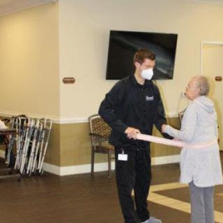 A healthcare worker assists an elderly woman during a physical therapy session in a warm and welcoming environment.