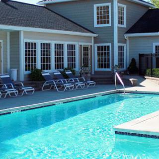 A residential swimming pool with lounge chairs on a sunny day.