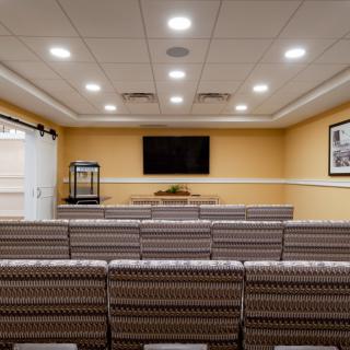 A well-lit meeting room with rows of seats facing a television screen, suitable for presentations or conferences.