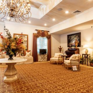 An elegantly decorated living room with a chandelier, plush seating, and warm-toned decor.
