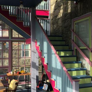 A brightly colored interior featuring a staircase with vibrant accents, bathed in sunlight.