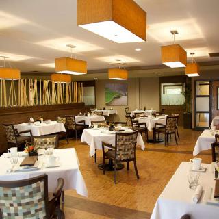 A modern and elegantly designed restaurant interior featuring neatly arranged tables and chairs, with warm lighting creating a welcoming ambience.