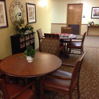 A cozy dining area with several tables and chairs, decorated with artwork and plants.