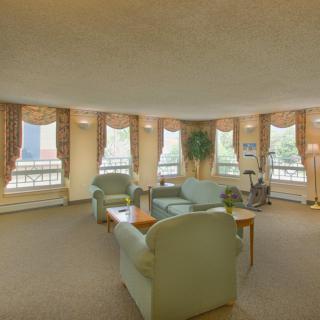 A spacious living room with ample natural light, featuring sofas and a coffee table arranged around large windows.