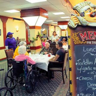 Residents enjoying a meal in the community dining area of a senior living facility.