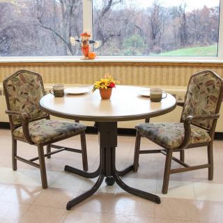A small round dining table with two upholstered chairs, set near a window overlooking a scenic view.