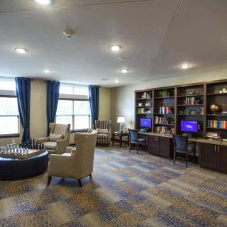 A cozy library space with bookshelves, computers, and comfortable seating.
