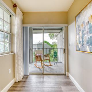 Bright room with a sliding glass door leading to a cozy balcony area featuring chairs and a table.