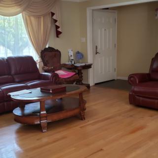 A cozy living room with leather sofas, a wooden coffee table, and large windows with curtains.