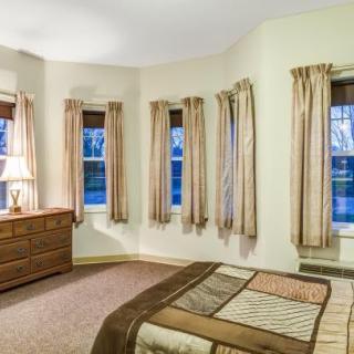 A cozy bedroom with multiple windows, a bed, and a dresser.