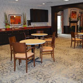 A cozy interior space with tables and chairs, decorated with artwork and ambient lighting.