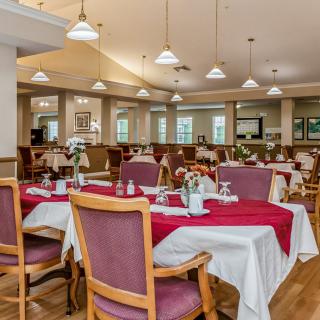 A well-lit restaurant dining area with neatly arranged tables and chairs, featuring elegant decor.