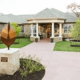A welcoming building entrance with a landscaped path and a modern sculpture.