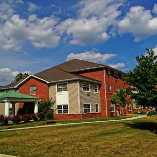 A suburban residential apartment building under a partly cloudy sky.