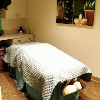 A tranquil massage room with a neatly made bed, ideal for relaxation and therapy.