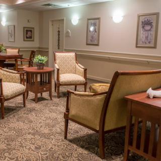 A cozy lounge area with multiple chairs and tables, adorned with decorative elements and a carpeted floor.